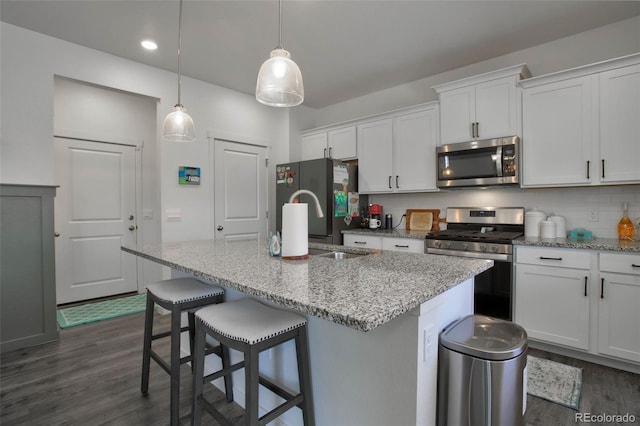 9 N Waterloo St, Aurora, CO 80018 - kitchen with appliances with stainless steel finishes, dark wood-type flooring, white cabinets, a kitchen island with sink, and decorative light fixtures