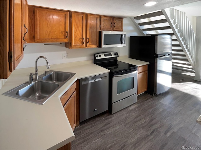 kitchen with a textured ceiling, sink, stainless steel appliances, and dark wood-type flooring