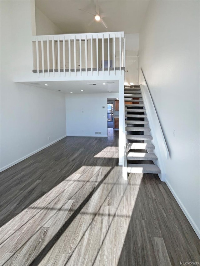 stairs with hardwood / wood-style flooring and a high ceiling