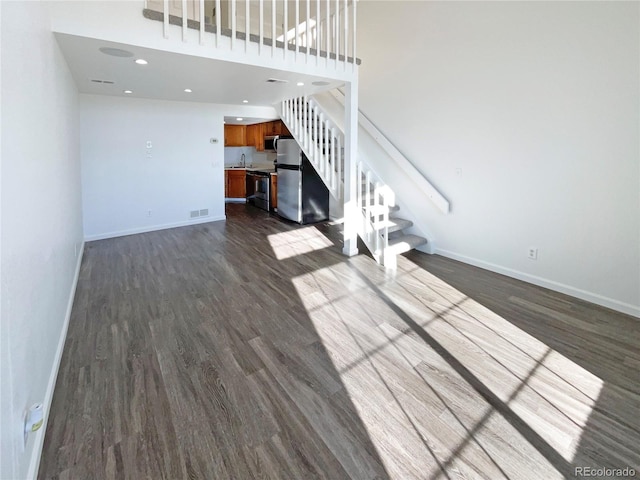 unfurnished living room featuring sink, a high ceiling, and dark hardwood / wood-style floors