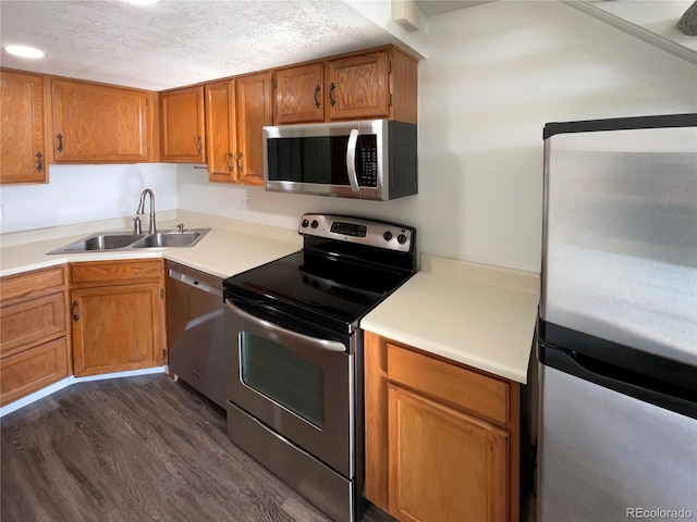 kitchen with a textured ceiling, dark hardwood / wood-style flooring, stainless steel appliances, and sink