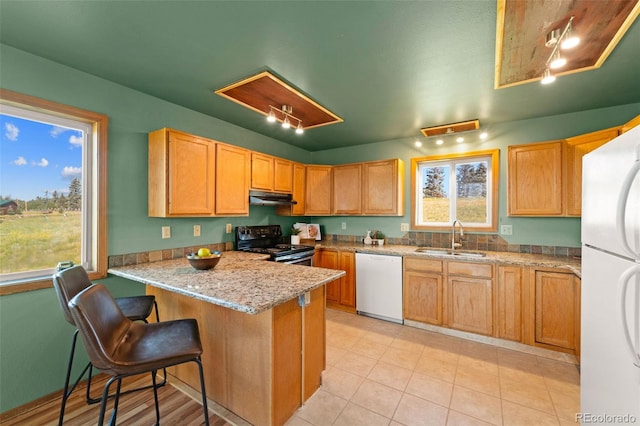 428 Ridge Dr, Divide, CO 80814 - kitchen with white appliances, a peninsula, under cabinet range hood, light tile patterned flooring, and a breakfast bar