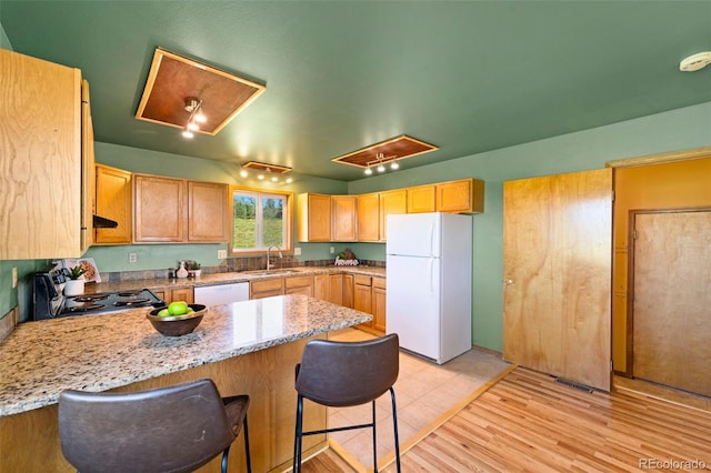 428 Ridge Dr, Divide, CO 80814 - kitchen featuring a peninsula, white appliances, a kitchen bar, light stone counters, and light wood finished floors