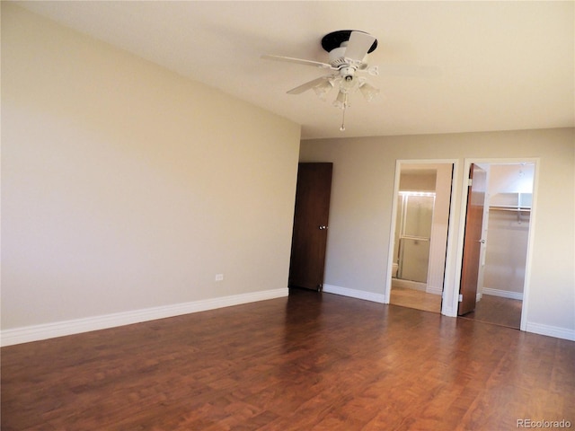 unfurnished bedroom with a spacious closet, a closet, wood finished floors, and baseboards