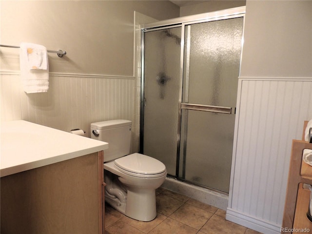 bathroom with tile patterned flooring, a wainscoted wall, and a shower stall