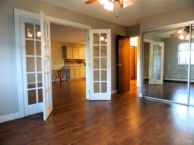 empty room featuring a baseboard heating unit, french doors, ceiling fan, and dark wood-style flooring