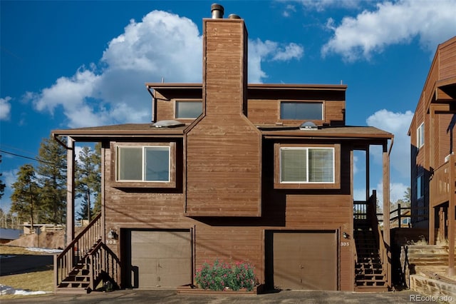 chalet / cabin featuring stairs, a garage, and a chimney