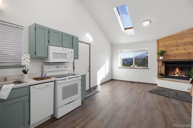 kitchen featuring dark wood-type flooring, lofted ceiling with skylight, light countertops, a lit fireplace, and white appliances