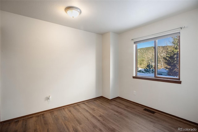 spare room featuring visible vents, baseboards, and wood finished floors