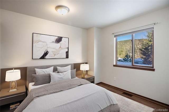 bedroom featuring wood finished floors, visible vents, and baseboards