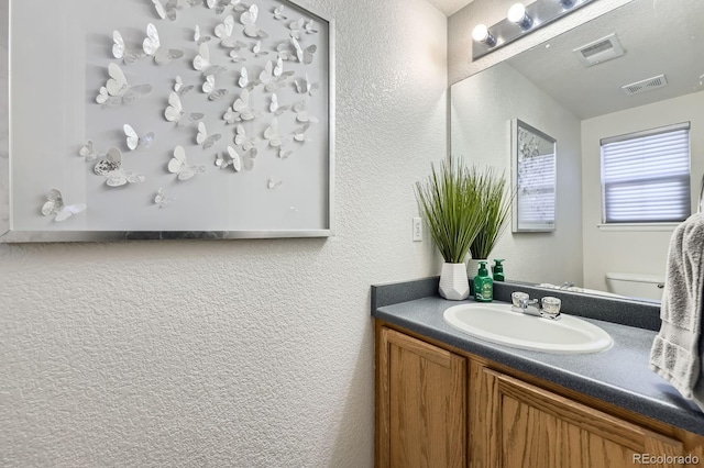 bathroom featuring a textured wall, visible vents, and vanity