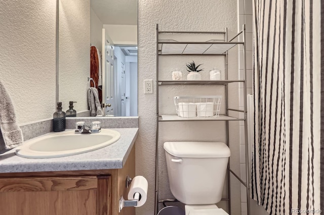 full bathroom featuring a shower with curtain, a textured wall, vanity, and toilet