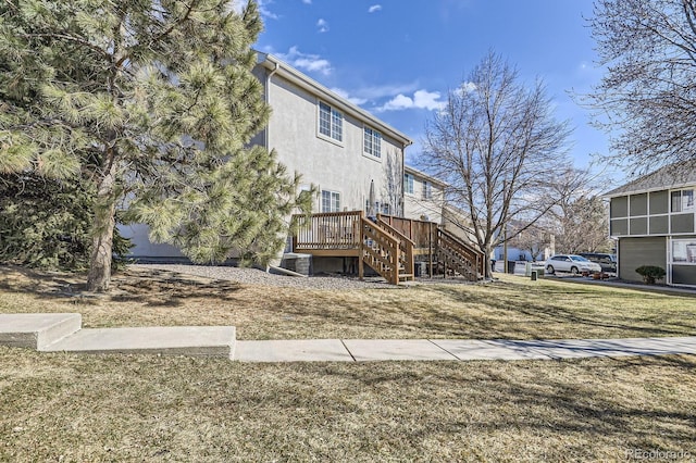 view of side of home with stucco siding, a lawn, stairway, central AC unit, and a deck