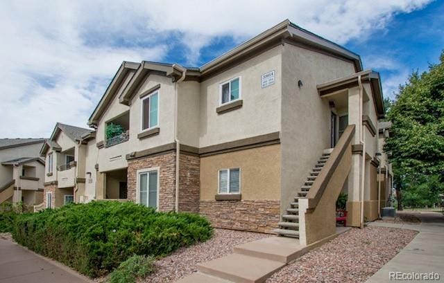 view of side of property with stone siding, stairway, and stucco siding