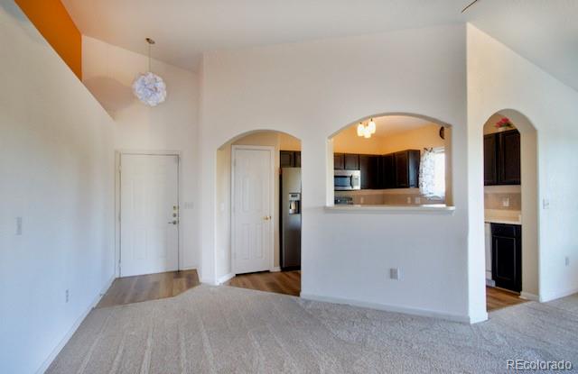 carpeted empty room featuring lofted ceiling and an inviting chandelier