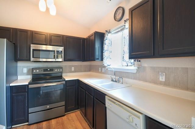 3864 Riviera Grv Unit 204, Colorado Springs, CO 80922 - kitchen featuring a sink, vaulted ceiling, light wood-style floors, light countertops, and appliances with stainless steel finishes