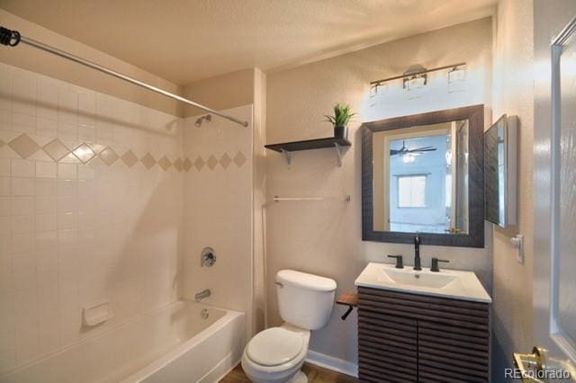 full bathroom featuring tiled shower / bath, vanity, toilet, and ceiling fan