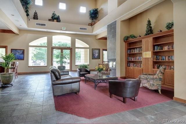 sitting room with a towering ceiling, baseboards, and visible vents