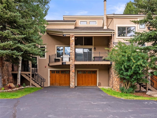 view of property featuring stairs, driveway, a garage, and stucco siding