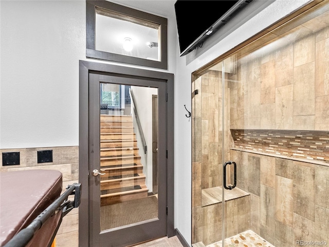 interior space with a wainscoted wall and a shower stall