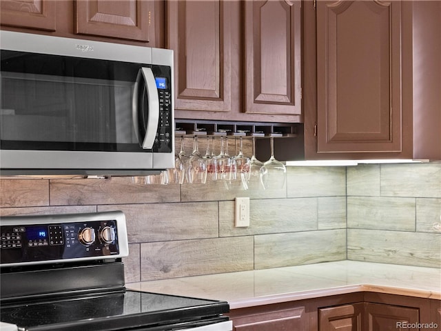 kitchen featuring light countertops, stainless steel microwave, electric range, and decorative backsplash