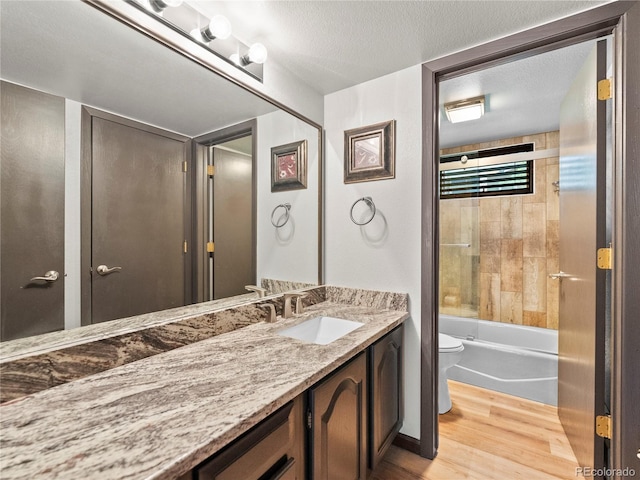 bathroom with toilet, vanity, a textured ceiling, and wood finished floors