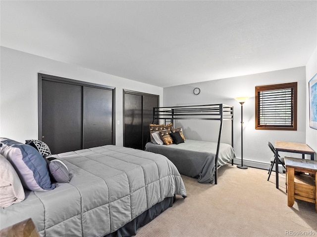 carpeted bedroom featuring a baseboard radiator and multiple closets