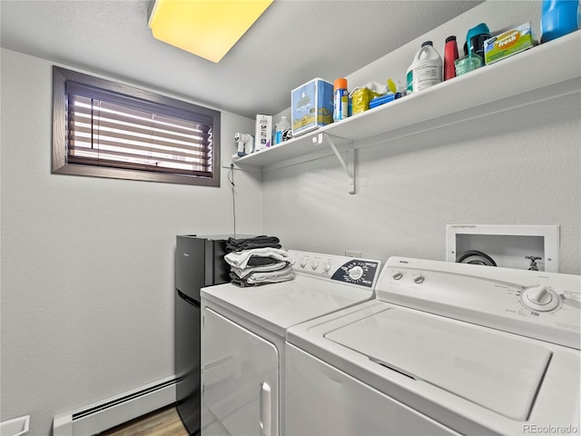 laundry area with laundry area, a textured wall, a baseboard radiator, wood finished floors, and washer and dryer