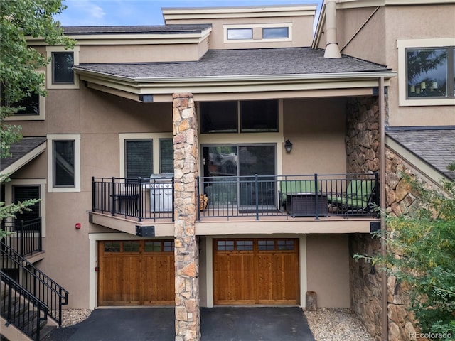 back of house with stairs, driveway, an attached garage, and stucco siding