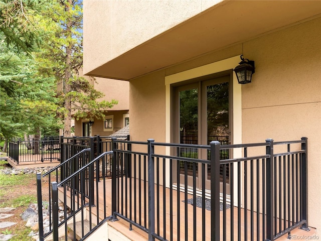 view of exterior entry with a balcony and stucco siding