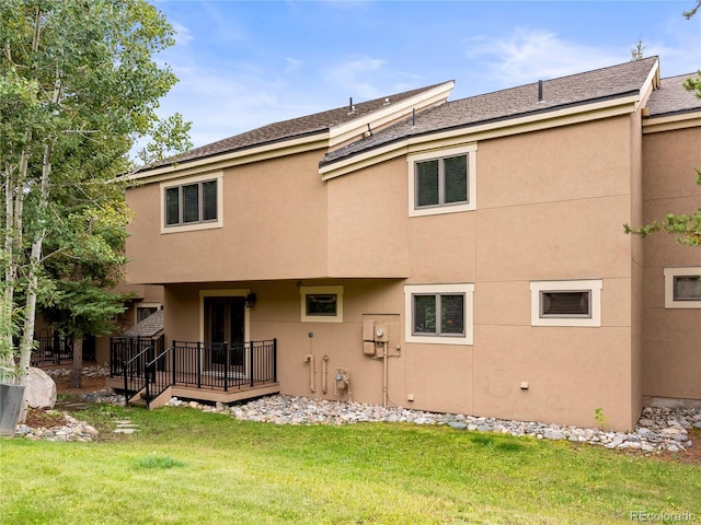 back of property with a lawn and stucco siding