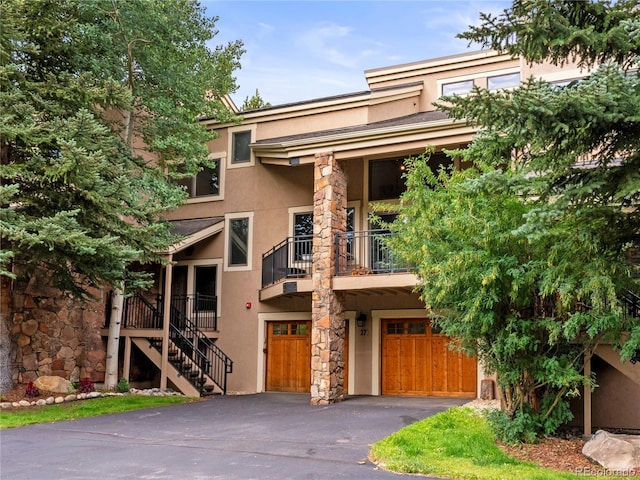 view of front of property with a garage, driveway, stairway, and stucco siding