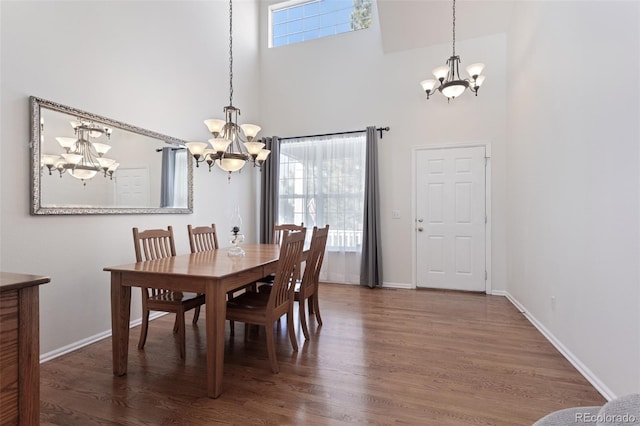 dining area featuring a high ceiling, dark hardwood / wood-style flooring, and a chandelier