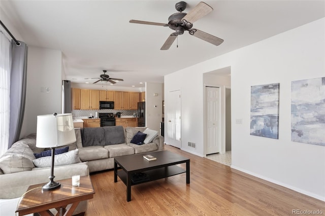 living room featuring ceiling fan and light hardwood / wood-style floors