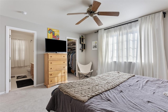 carpeted bedroom with ceiling fan, a walk in closet, a closet, and ensuite bath