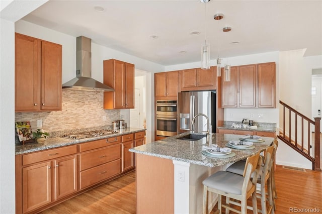 8926 Swan River St, Littleton, CO 80125 - kitchen with wall chimney exhaust hood, appliances with stainless steel finishes, light wood-type flooring, light stone counters, and hanging light fixtures
