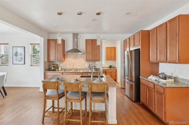 8926 Swan River St, Littleton, CO 80125 - kitchen with wall chimney range hood, appliances with stainless steel finishes, light wood-type flooring, a breakfast bar area, and recessed lighting