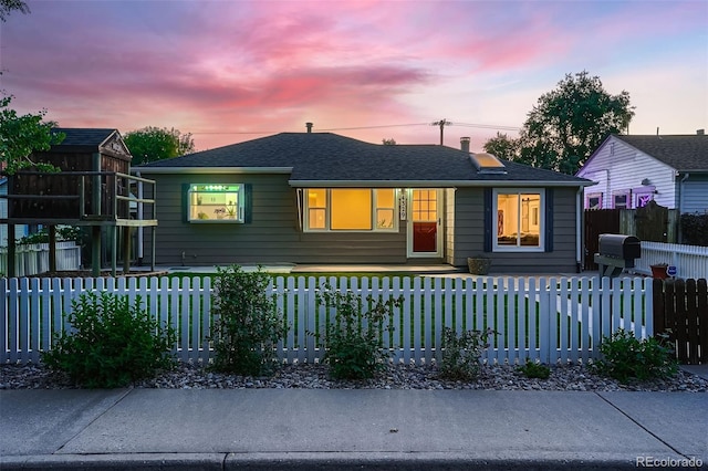 view of front of property featuring a fenced front yard and roof with shingles