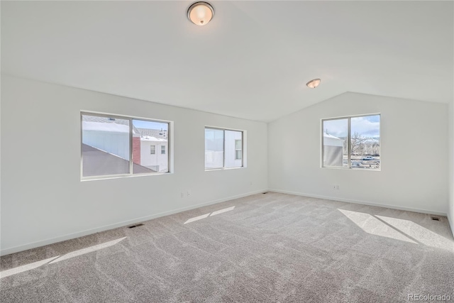 carpeted spare room with vaulted ceiling