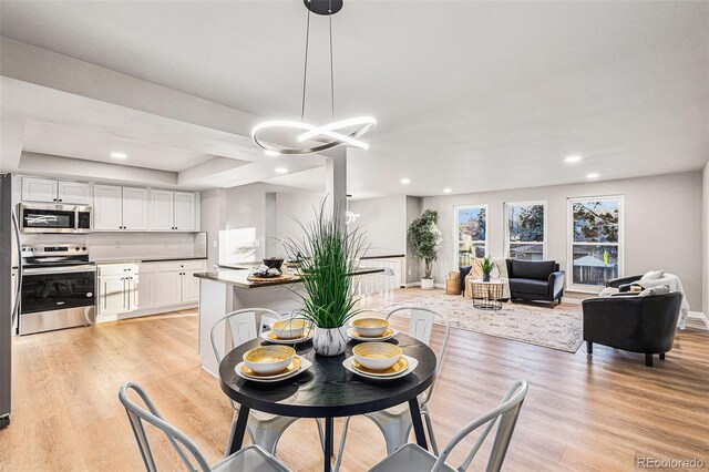 dining space featuring a tray ceiling and light hardwood / wood-style flooring