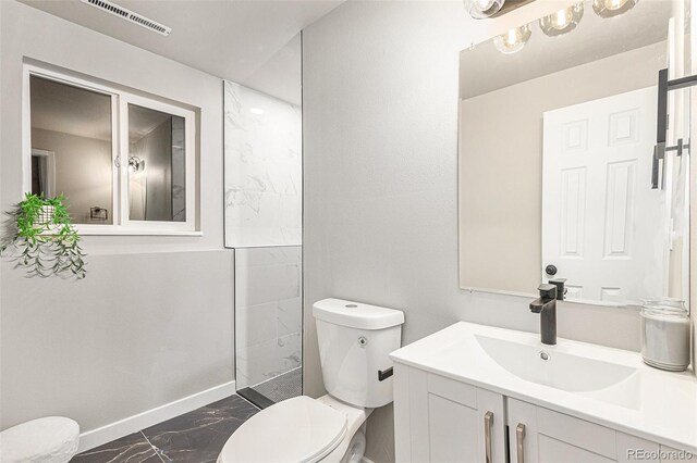 bathroom featuring walk in shower, vanity, and toilet