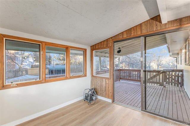 unfurnished sunroom featuring lofted ceiling with beams and plenty of natural light