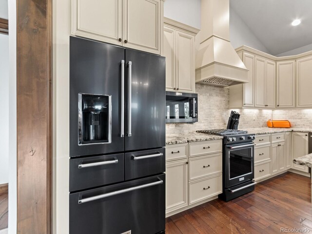 3124 Antelope Ridge Trl, Parker, CO 80138 - kitchen featuring premium appliances, custom exhaust hood, cream cabinetry, dark wood-type flooring, and tasteful backsplash