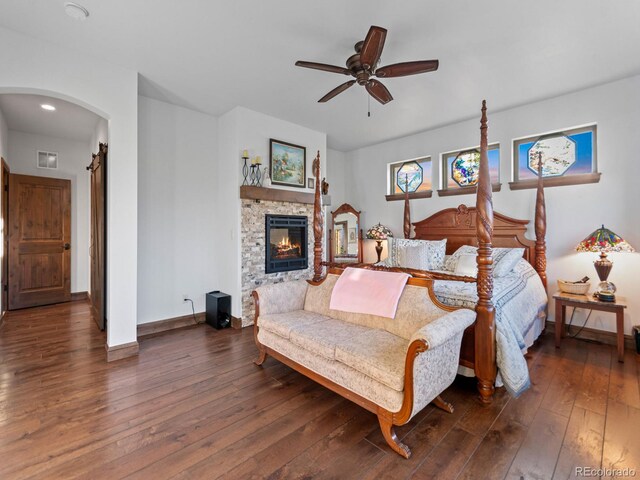 3124 Antelope Ridge Trl, Parker, CO 80138 - bedroom with dark wood-type flooring, a fireplace, arched walkways, a ceiling fan, and recessed lighting