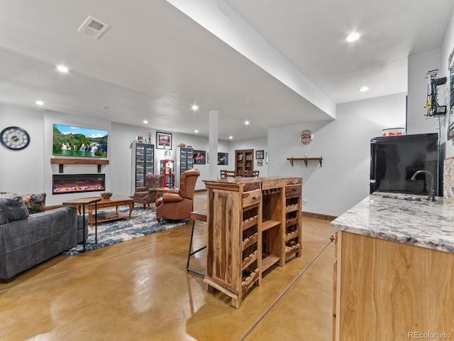 3124 Antelope Ridge Trl, Parker, CO 80138 - living room with finished concrete flooring, recessed lighting, bar area, and a glass covered fireplace