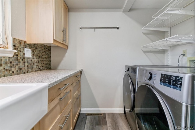 laundry room with washing machine and dryer, dark wood-type flooring, cabinet space, and baseboards