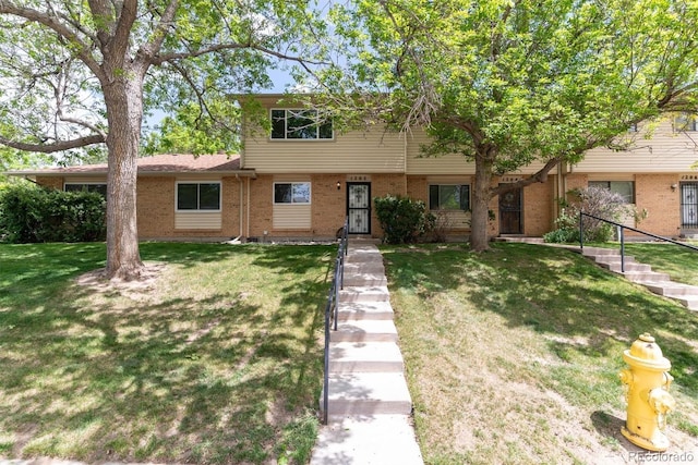 townhome / multi-family property with a front yard and brick siding