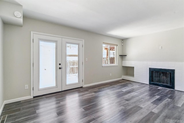 unfurnished living room with french doors, wood finished floors, a fireplace, and baseboards