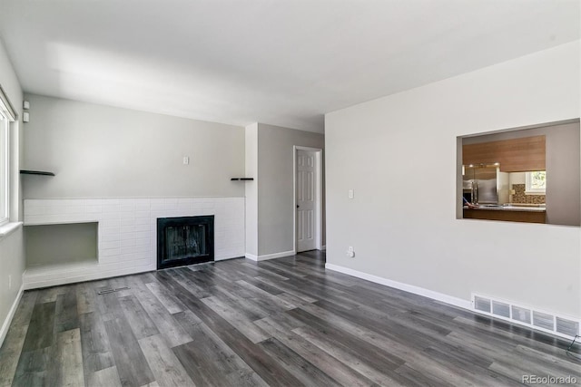 unfurnished living room with dark wood-style floors, a fireplace, and baseboards