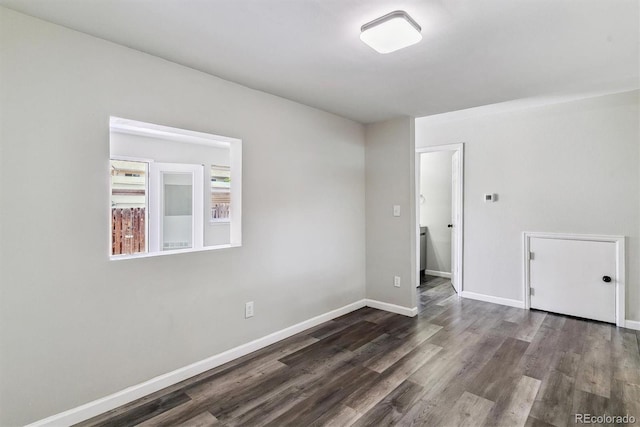 spare room featuring dark wood-style floors and baseboards